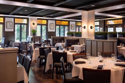 a restaurant with white tables and chairs and windows at Four Points by Sheraton Norwood Conference Center in Norwood