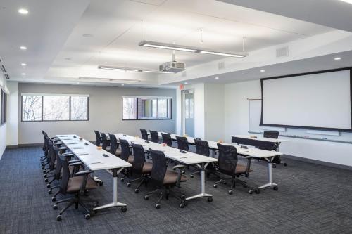 a conference room with tables and chairs and a white screen at Four Points by Sheraton Norwood Conference Center in Norwood