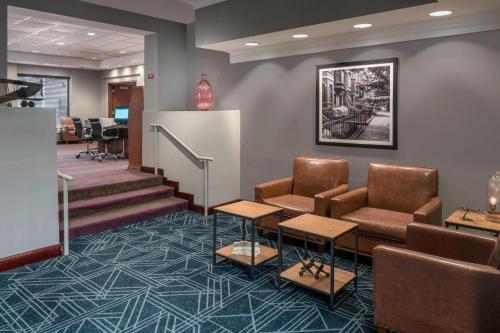 a lobby with a waiting room with chairs and stairs at Four Points by Sheraton Boston Logan Airport Revere in Revere