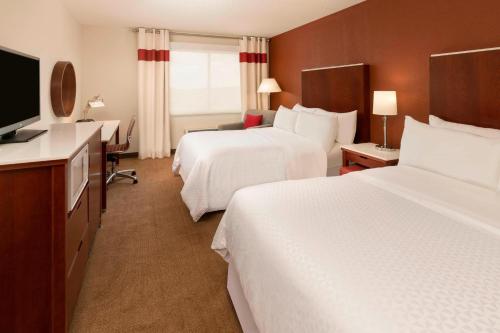 a hotel room with two beds and a flat screen tv at Four Points by Sheraton Boston Logan Airport Revere in Revere