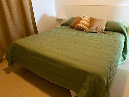 a green bed with pillows on it in a bedroom at Cabañas Lomas de Calamuchita in Santa Rosa de Calamuchita