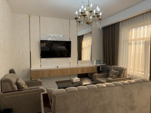 a living room with a couch and chairs and a television at Aram Hotel in Dushanbe