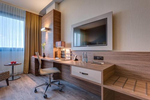 a hotel room with a desk and a television on a wall at Bonn Marriott Hotel in Bonn