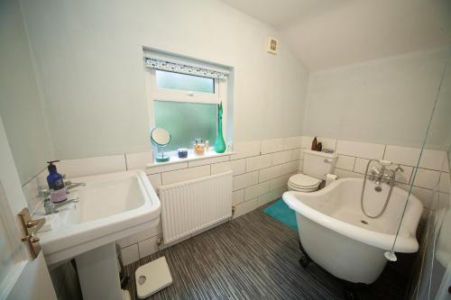 a bathroom with a sink and a tub and a toilet at Pheasant's Bank holiday cottage in Chapel en le Frith