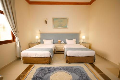 a bedroom with two beds and a rug at Al Bada Hotel and Resort in Al Ain