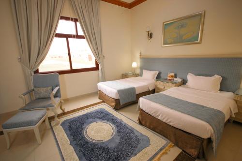 a hotel room with two beds and a chair and a window at Al Bada Hotel and Resort in Al Ain