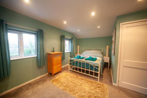 a bedroom with green walls and a bed and a window at Pheasant's Bank holiday cottage in Chapel en le Frith