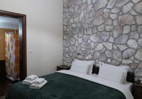 a bedroom with a stone wall and a bed with two towels at Rooms Batalogianni in Kalabaka