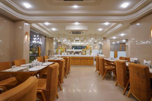 a restaurant with wooden tables and chairs and a counter at Artilla Inn in Ahmedabad