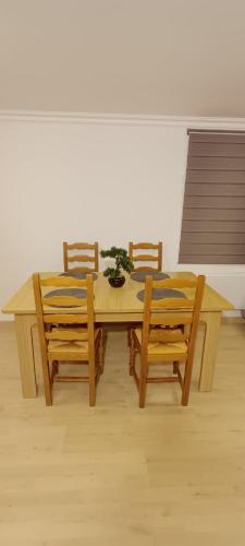 a wooden table with four chairs and a table with a plant on it at Maison Stival in Pontivy
