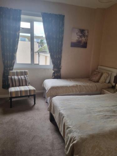 a bedroom with two beds and a chair and a window at The Sands Hotel in Paignton