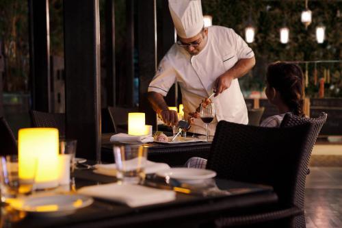 a chef preparing food at a table in a restaurant at Four Points by Sheraton Hotel and Serviced Apartments Pune in Pune