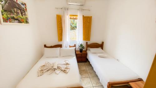 two beds in a room with white walls at Pousada Canto dos Pássaros in Lençóis