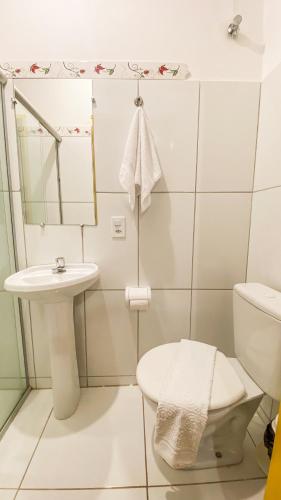 a white bathroom with a toilet and a sink at Pousada Canto dos Pássaros in Lençóis