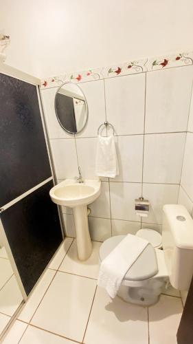 a bathroom with a toilet and a sink and a mirror at Pousada Canto dos Pássaros in Lençóis