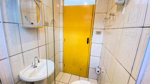 a bathroom with a sink and a yellow shower door at Pousada Canto dos Pássaros in Lençóis