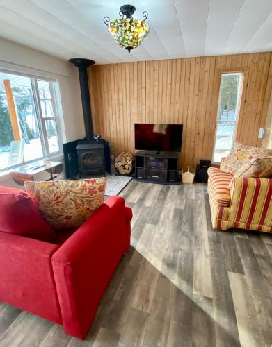 a living room with a red couch and a fireplace at Chalet Sous Les Pins in Les Éboulements
