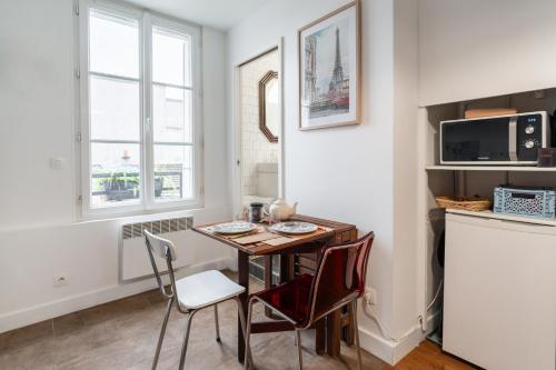 une cuisine avec une table et des chaises dans une pièce dans l'établissement Le Vinted Chic - 15 min des Champs-Elysées, à Saint-Ouen