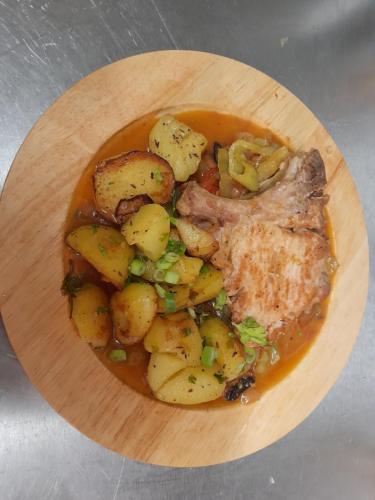a wooden plate of food with potatoes and meat at Pension Jana - Wellness in Jilemnice