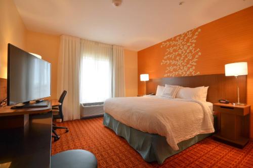 a hotel room with a bed and a flat screen tv at Fairfield Inn & Suites by Marriott St. Louis Pontoon Beach/Granite City, IL in Collinsville