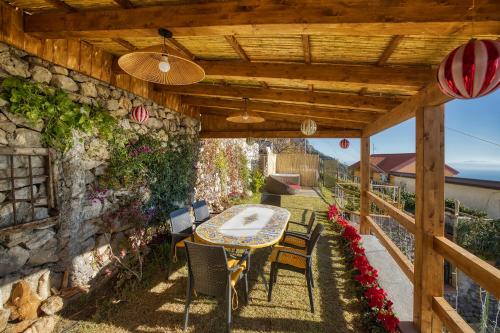 a patio with a table and chairs under a wooden pergola at Salvo's House in Furore