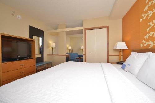a hotel room with a bed and a flat screen tv at Fairfield Inn and Suites by Marriott Williamsport in Williamsport