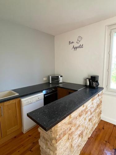 une cuisine avec un comptoir noir dans une pièce dans l'établissement La Maison Lilas, à Messeix