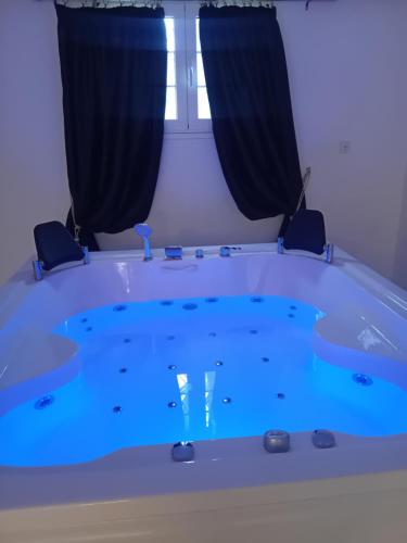 a tub with blue water in a room with a window at Meteora Grande luxury suite & spa villa in Kalabaka