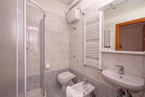 a bathroom with a toilet and a sink and a shower at GH Hotel Piaz in Pozza di Fassa