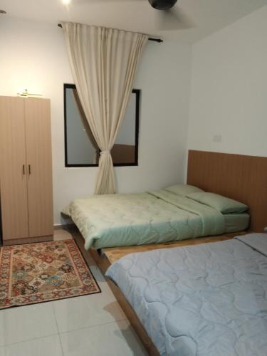 a bedroom with two beds and a window at Tiny Tijani Homestay in Kulai