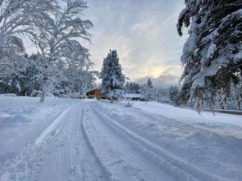 a snow covered road with a house and trees at Snowdon Chalet Motel in Londonderry
