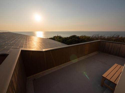 a balcony with a view of the ocean at sunset at 1日1組限定1棟貸し別荘 RivageBlue in Yawata