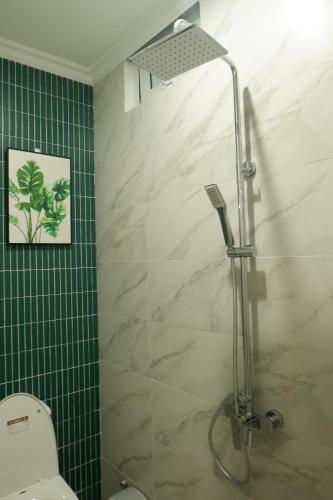 a bathroom with a shower with a toilet and green tiles at Camellia Full House in Da Nang