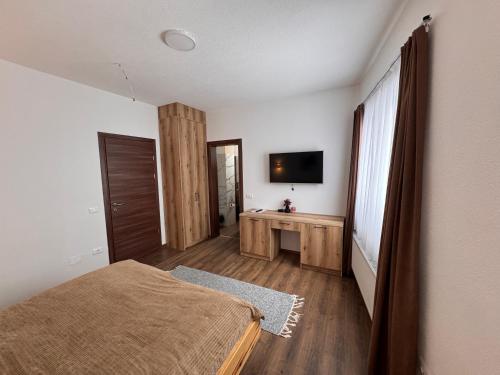 a bedroom with a bed and a flat screen tv at Casa Leone Hotel&Restaurant in Popova Shapka