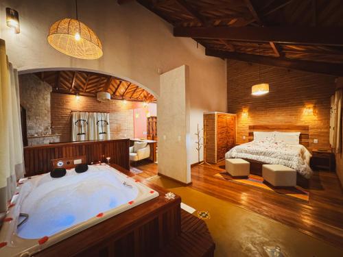a bedroom with a large tub and a bed at Chalé Seio de Minas in Gonçalves