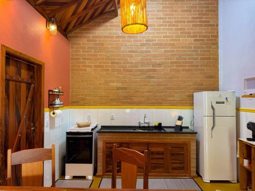 a kitchen with a white refrigerator and a table and chairs at Chalé Seio de Minas in Gonçalves