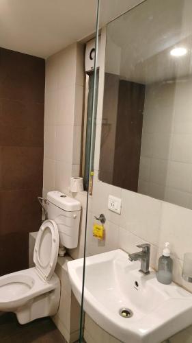 a bathroom with a toilet and a sink and a mirror at Rajhansh Belliza Nest - A Luxury 2BHK Apartment in Surat