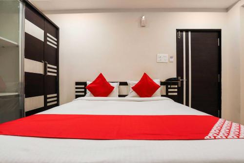a bedroom with a large white bed with red pillows at Hotel O Sr Residency in Vijayawāda