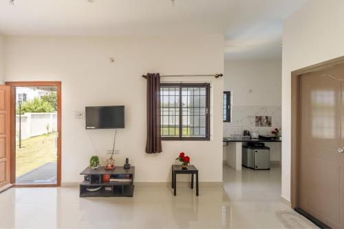 a kitchen and a living room with a tv on the wall at JhilMil Pool Villa by StayJadeParty VillaLawn in Hosūr