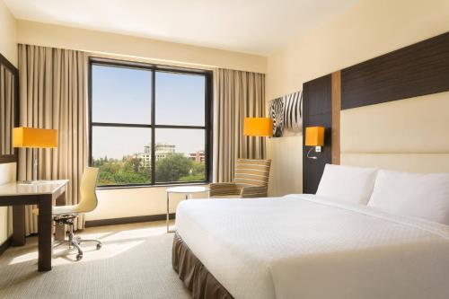 a hotel room with a bed and a desk and a window at Four Points By Sheraton Nairobi Hurlingham in Nairobi