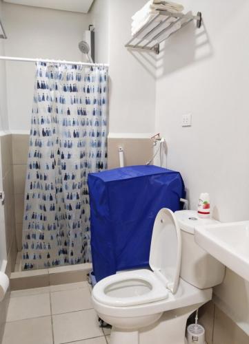 a bathroom with a toilet with a blue shower curtain at APT at G-207 in SMDC Cheer Residences in Marilao