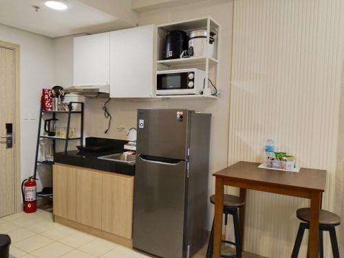 a kitchen with a stainless steel refrigerator and a table at APT at G-207 in SMDC Cheer Residences in Marilao