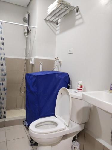 a bathroom with a toilet with a blue shower curtain at APT at G-207 in SMDC Cheer Residences in Marilao