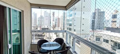 a balcony with a table and a view of a city at Apto 350 metros do mar com 2 garagens e ar condicionado in Meia Praia