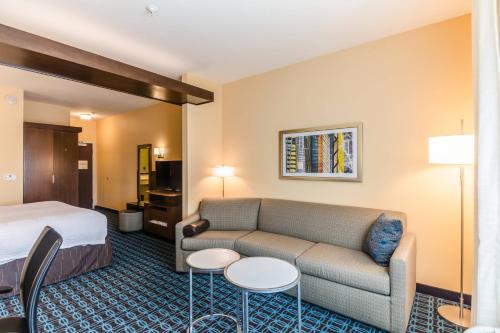 a hotel room with a bed and a couch and tables at Fairfield Inn & Suites by Marriott Panama City Beach in Panama City Beach