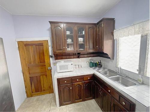 a kitchen with wooden cabinets and a sink and a microwave at Close to Beach-Perfect Location in Puerto Cortes