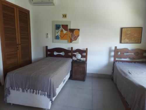 a bedroom with two beds and a night stand in it at Casa CANTIN DO ACONCHEGO na Praia de Taperapuan, Porto Seguro in Porto Seguro
