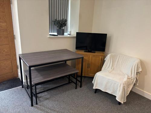 a room with a table and a chair and a television at Jubilee Works in Chesterfield