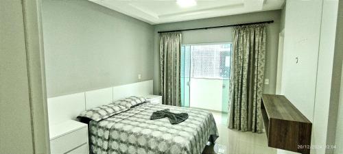 a bedroom with a bed and a mirror and a window at Apto 350 metros do mar com 2 garagens e ar condicionado in Meia Praia