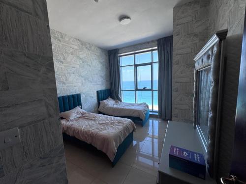a hotel room with two beds and a window at Sunrise Ajman sea view in Ajman 